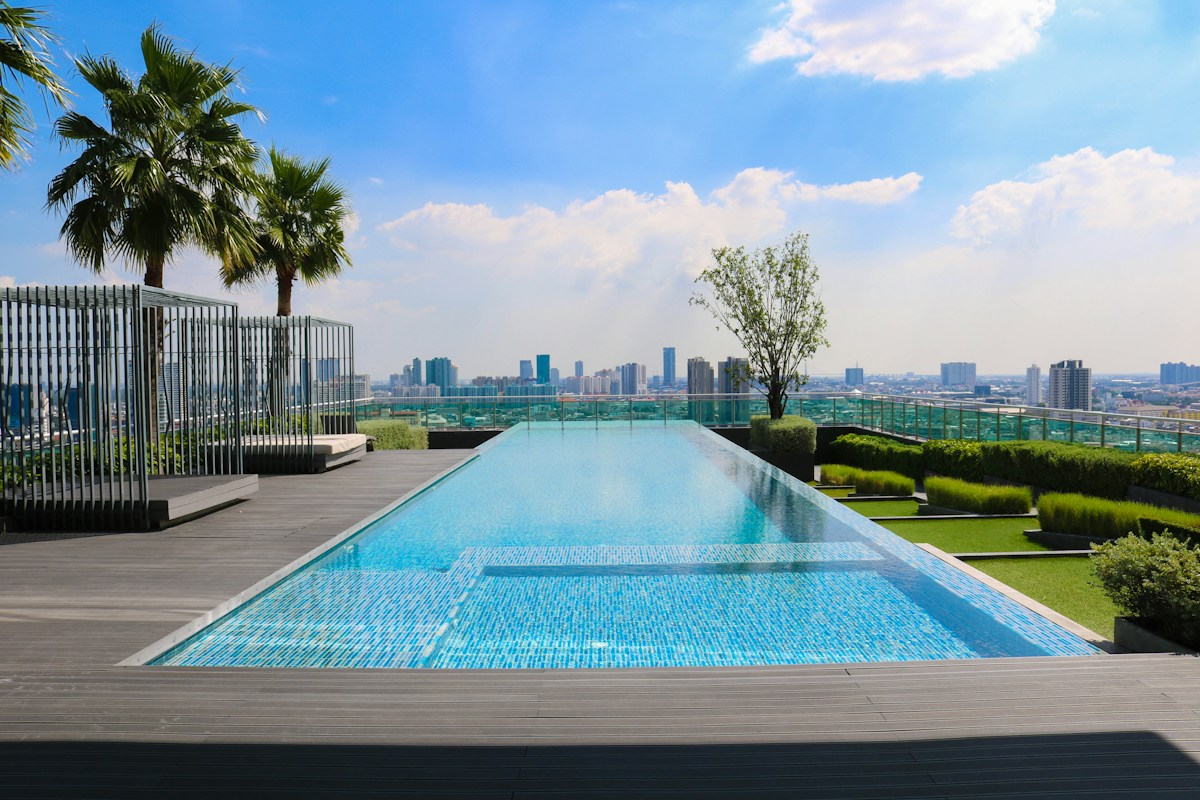 Blue pool beside a landscaped terrace overlooking city buildings; illustrative photography